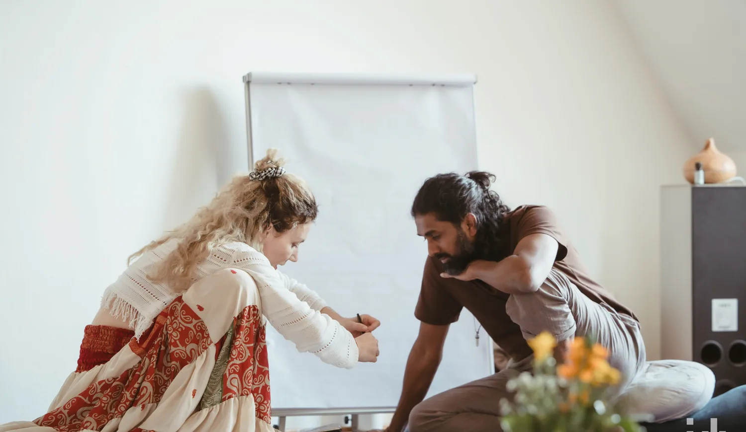 Ahilan und Sofie sitzen während eines Trainings gemeinsam mit einem Flipchart