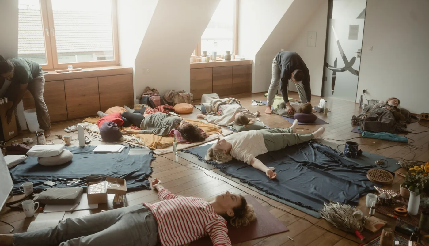 Teilnehmende ruhen auf Matten in einem hellen Raum mit schrägen Decken während einer innerdance Session